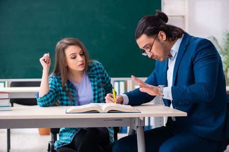 Young handsome teacher and female student in the classroomの写真素材