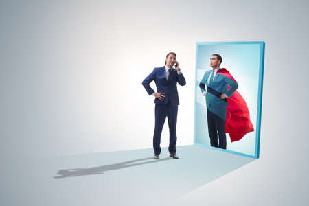 Businessman seeing himself in mirror as superheroの写真素材