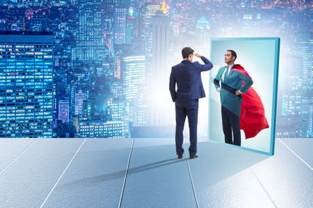 Businessman seeing himself in mirror as superheroの写真素材
