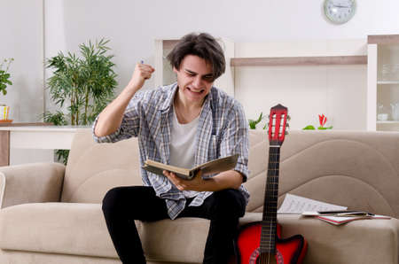 Young man with guitar at homeの写真素材