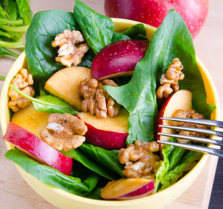 Spinach salad with nuts and apples served on tableの写真素材
