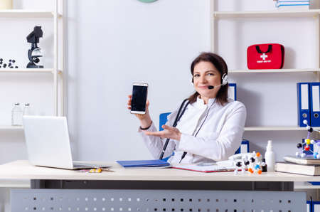 Middle-aged female doctor in telemedicine conceptの写真素材