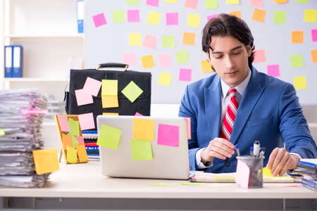 Young male handsome employee in conflicting priorities conceptの写真素材