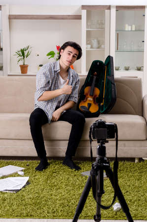 Young male blogger playing violin at homeの写真素材