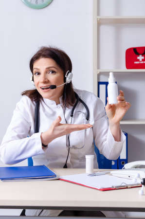 Middle-aged female doctor in telemedicine conceptの写真素材