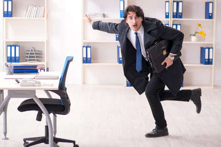 Young male employee in the office in time management conceptの写真素材