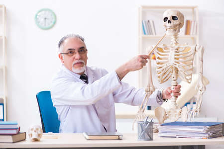 Aged male doctor with skeleton