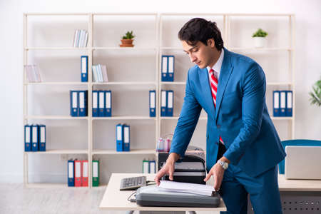 Young employee making copies at copying machineの写真素材