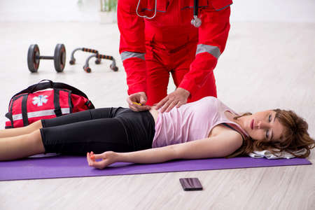 Paramedic in red visiting young woman in gymの写真素材