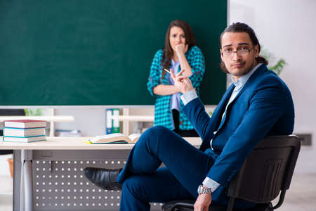 Young handsome teacher and female student in the classroomの写真素材