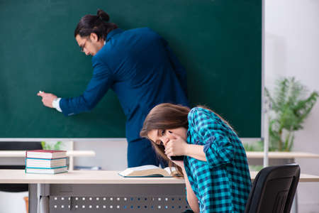 Young handsome teacher and female student in the classroomの写真素材