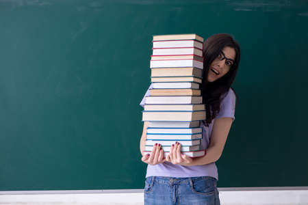 Young female teacher student in front of green boardの写真素材