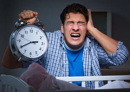 Young father under stress due to baby crying at nightの写真素材