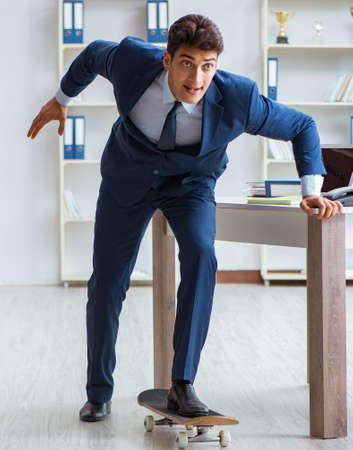 Young businessman with skate in office in sports conceptの写真素材