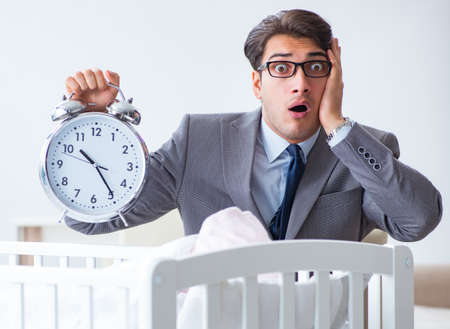 Young businessman trying to work from home caring after newbornの写真素材