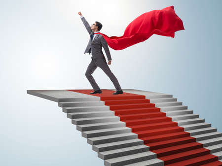 Superhero businessman climbing red carpet stairsの写真素材