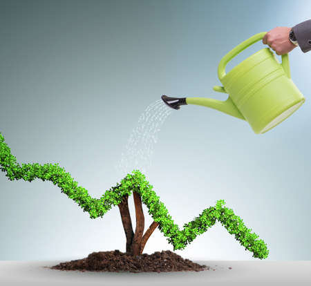 The businessman in investment concept watering financial line chartの写真素材