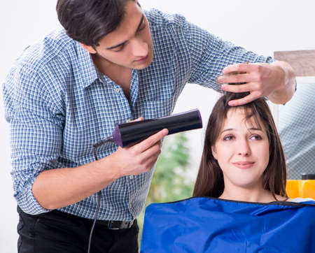 Man male hairdresser doing haircut for womanの写真素材