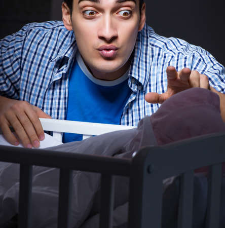 Happy dad looking after newborn baby at nightの写真素材