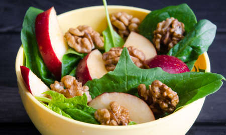 Spinach salad with nuts and apples served on tableの写真素材