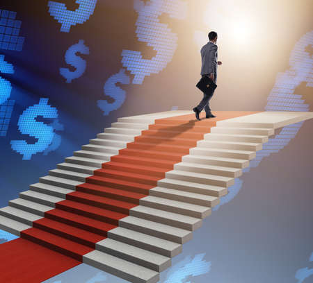 Young businessman climbing stairs and red carpetの写真素材