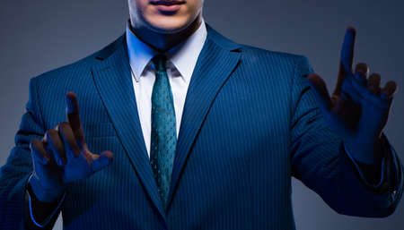 Businessman pressing virtual buttons on gray backgroundの写真素材