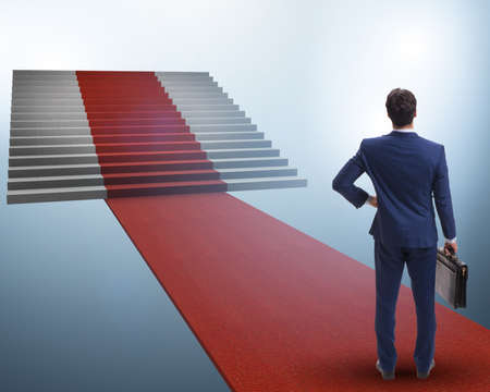 Young businessman climbing stairs and red carpetの写真素材