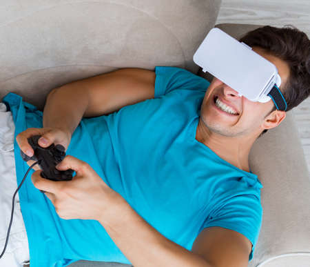 Young man wearing VR glasses relaxing on couch sofa