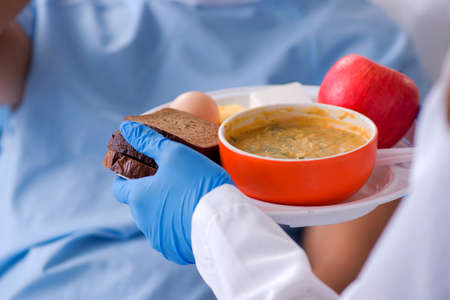 A nurse giving food to a male patient in a hospital, food closeup.