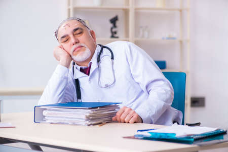 Old male doctor working in the clinicの写真素材