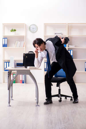 Young male employee in the office in time management conceptの写真素材