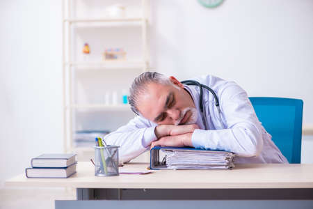 Old male doctor working in the clinicの写真素材