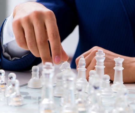 Young businessman playing glass chess in officeの写真素材