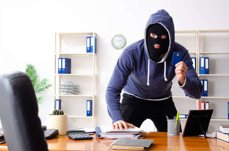 Male thief in balaclava in the officeの写真素材