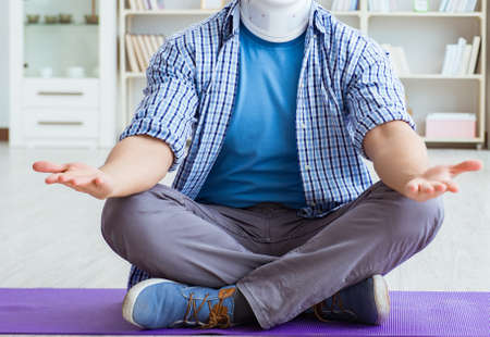 Man with neck injury meditating at home on floorの写真素材