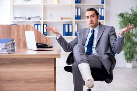 Leg injured male employee in the officeの写真素材