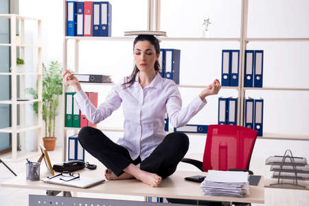 Young female employee doing exercises in the officeの写真素材