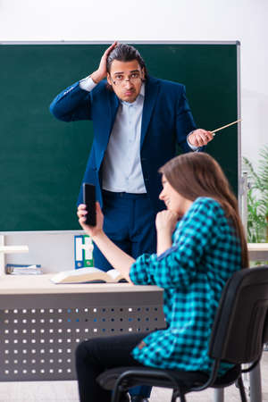 Young handsome teacher and female student in the classroomの写真素材
