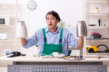 Young man repairing kettle in service centreの写真素材
