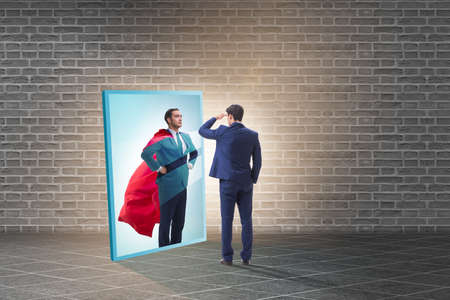 Businessman seeing himself in mirror as superheroの写真素材
