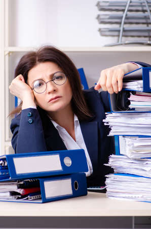 Middle-aged businesswoman unhappy with excessive workの写真素材