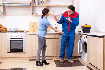 Young male repairman repairing washing machineの写真素材