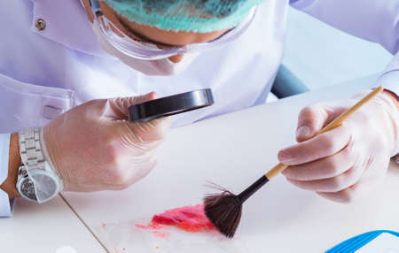 Criminologist police chemist looking at crime evidenceの写真素材