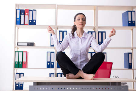 Young female employee doing exercises in the officeの写真素材