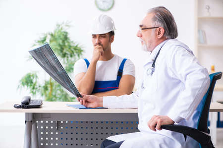 Young male contractor visiting old doctorの写真素材