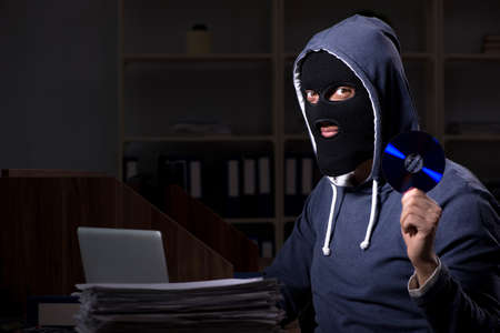 Male thief in balaclava in the office night timeの写真素材