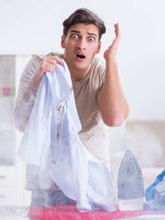 Inattentive husband burning clothing while ironingの写真素材