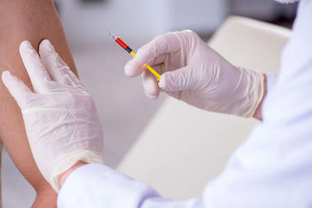 Male patient visitng doctor for shot inoculationの写真素材