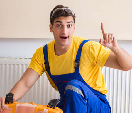 Young repairman contractor repairing heating panelの写真素材