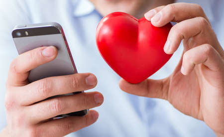 Young man chatting with his sweetheart over mobile phoneの写真素材
